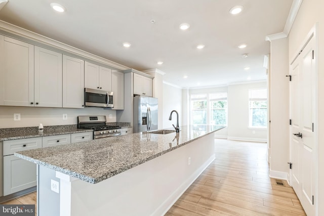 kitchen featuring light wood-type flooring, a center island with sink, appliances with stainless steel finishes, and sink