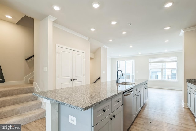 kitchen featuring light wood-type flooring, light stone counters, sink, a center island with sink, and stainless steel dishwasher