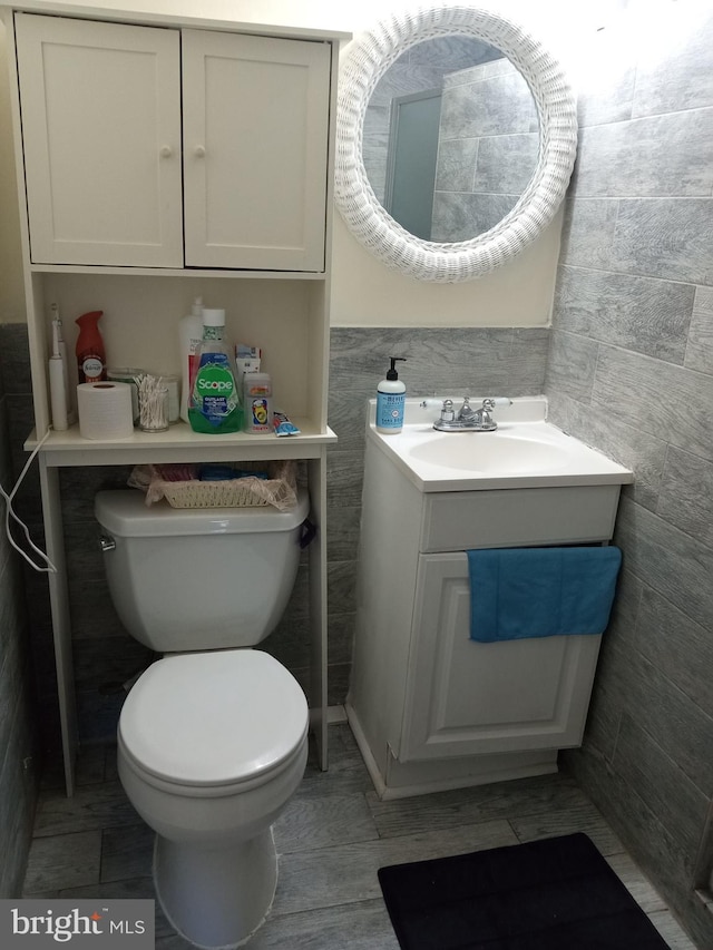 bathroom featuring vanity, toilet, and tile walls