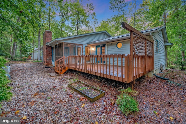 rear view of house with a wooden deck and a sunroom