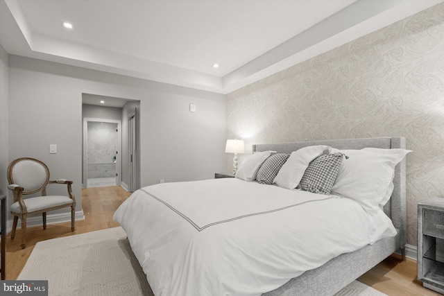 bedroom with ensuite bath and light hardwood / wood-style floors