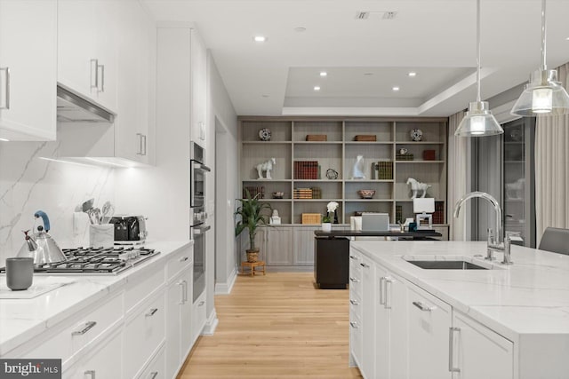 kitchen featuring pendant lighting, white cabinetry, a tray ceiling, and sink