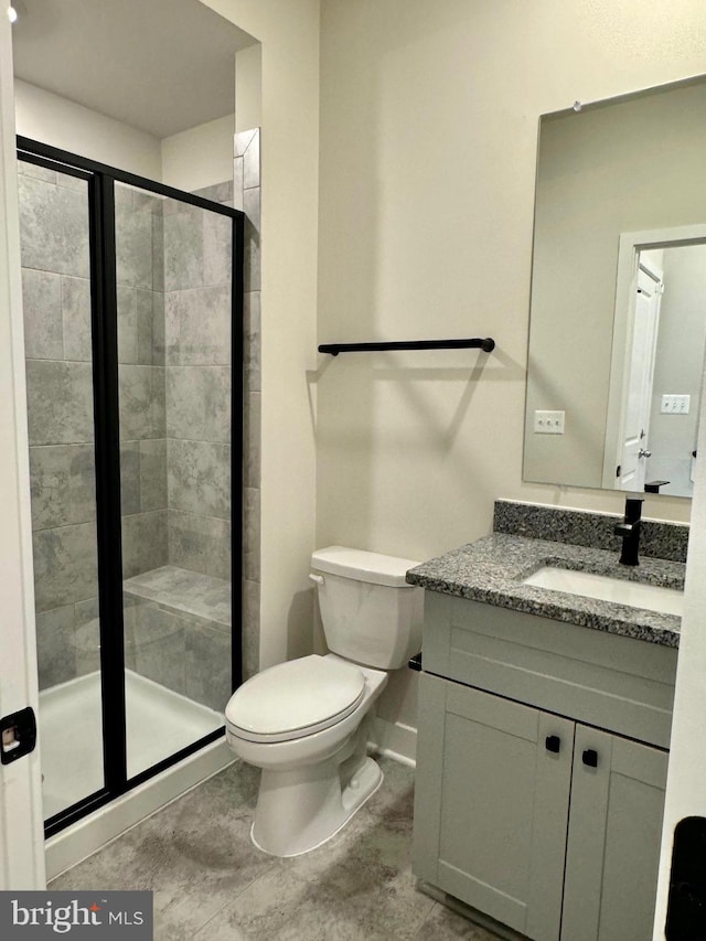 bathroom with vanity, toilet, and a shower with door