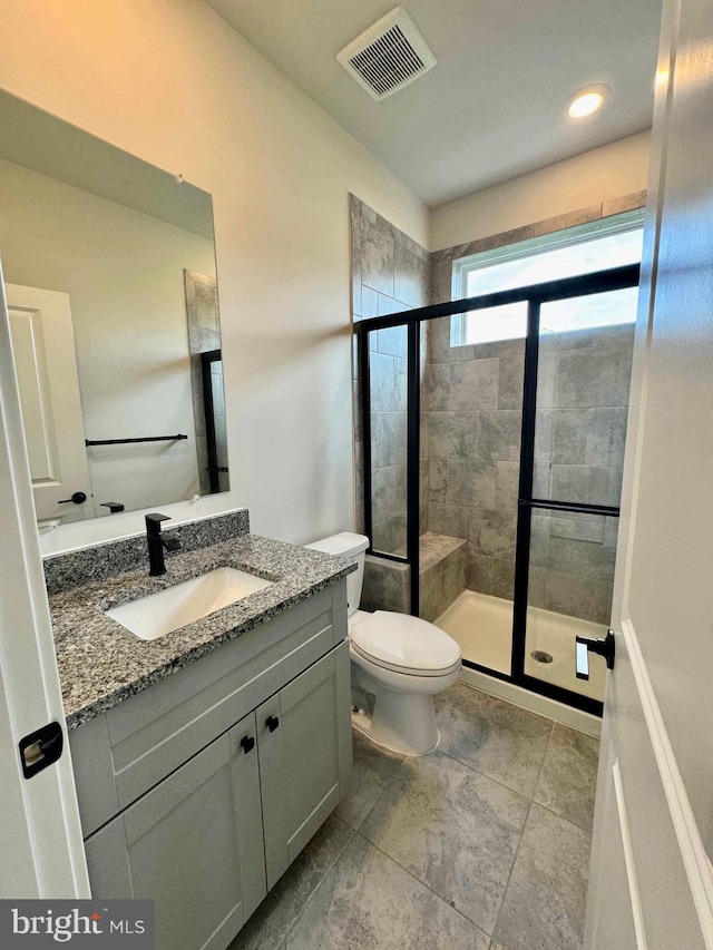 bathroom featuring an enclosed shower, vanity, and toilet