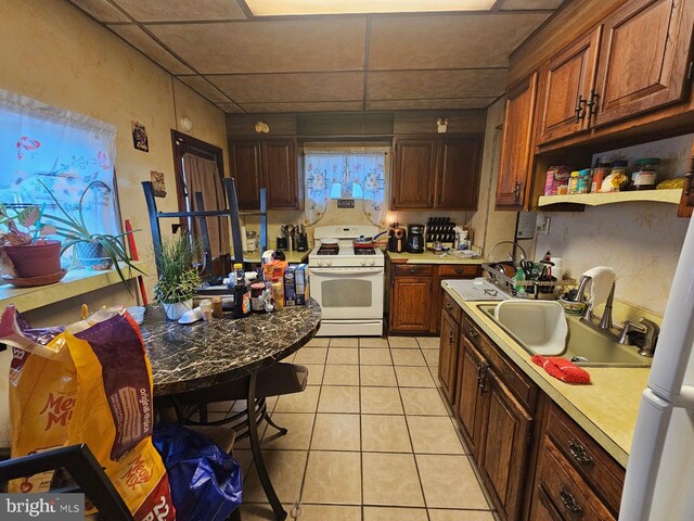 kitchen featuring a drop ceiling, light tile patterned flooring, sink, and white gas stove