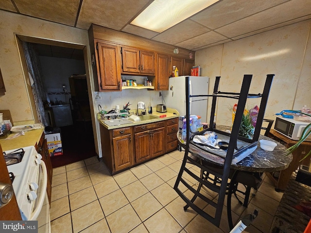 kitchen featuring light tile patterned flooring, sink, and white appliances