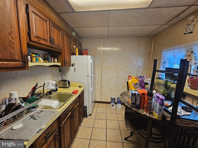 kitchen with a drop ceiling, light tile patterned floors, and sink