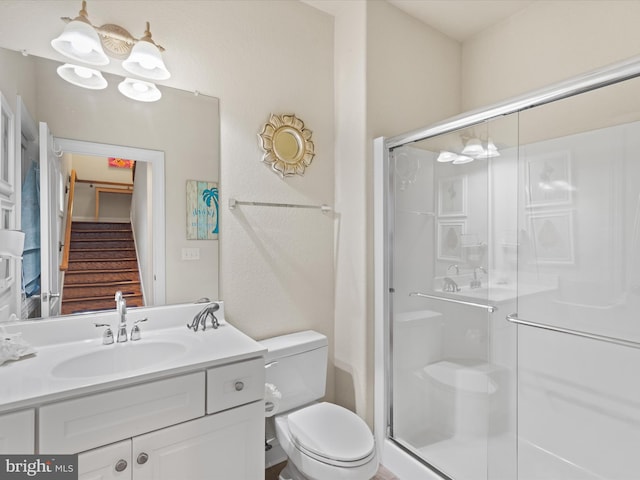 bathroom with walk in shower, vanity, and toilet