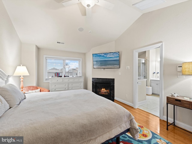 bedroom featuring lofted ceiling, ceiling fan, light hardwood / wood-style flooring, and ensuite bath