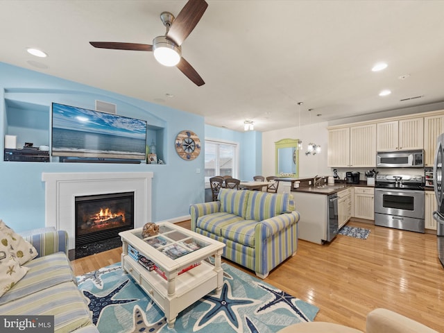 living room featuring light wood-type flooring, ceiling fan, and sink