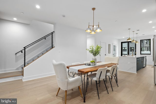 dining room with light wood-type flooring and a chandelier