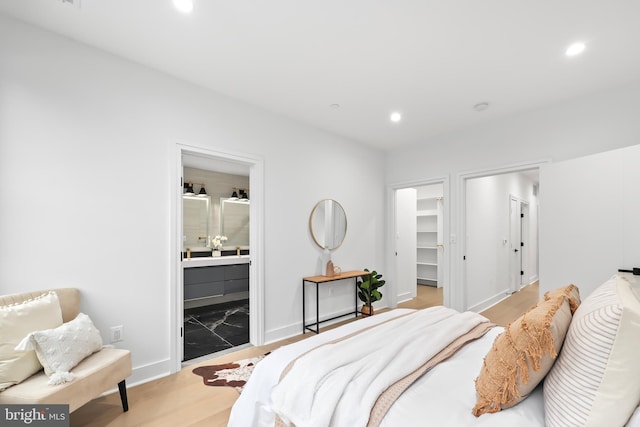 bedroom featuring a closet, connected bathroom, light hardwood / wood-style floors, and a spacious closet