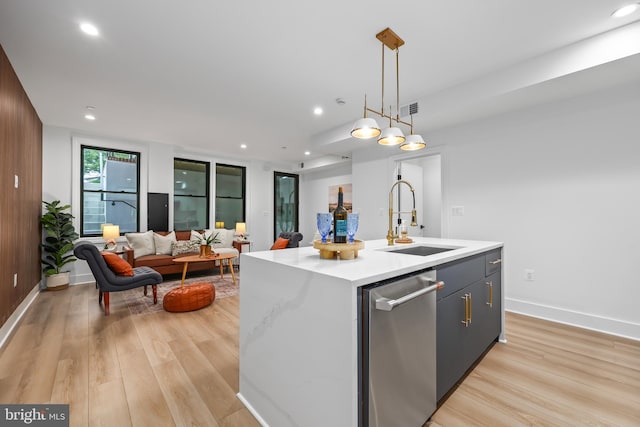 kitchen featuring light hardwood / wood-style floors, an island with sink, pendant lighting, stainless steel dishwasher, and sink