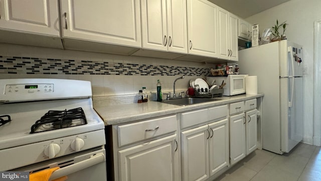 kitchen featuring tasteful backsplash, white cabinets, white appliances, light tile patterned floors, and sink