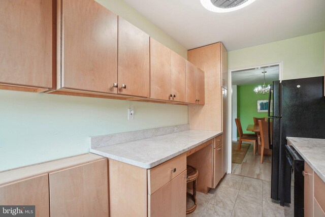 kitchen with light brown cabinets, a chandelier, and black appliances