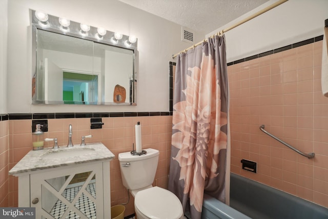 full bathroom with tile walls, shower / bath combo, vanity, and toilet