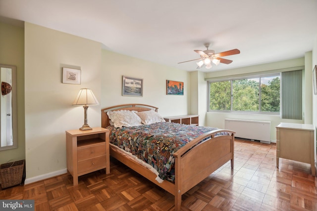 bedroom with ceiling fan, dark parquet floors, and radiator heating unit