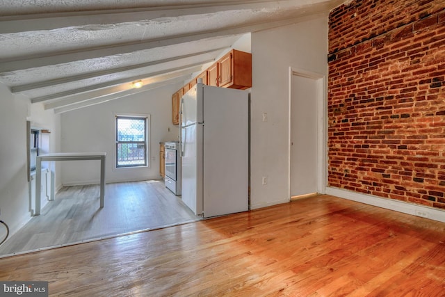 kitchen with light wood-type flooring, white refrigerator, a textured ceiling, vaulted ceiling with beams, and stainless steel range