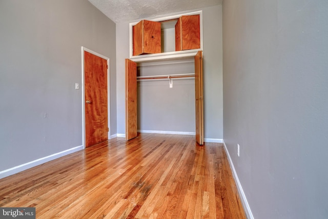 unfurnished bedroom with a textured ceiling, light hardwood / wood-style flooring, and a closet