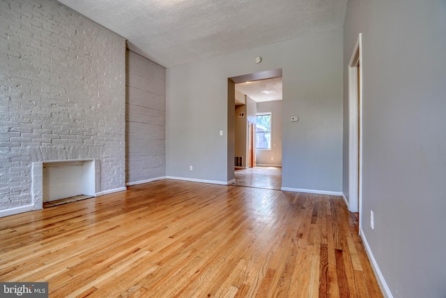 unfurnished living room featuring a textured ceiling, light hardwood / wood-style floors, and a fireplace