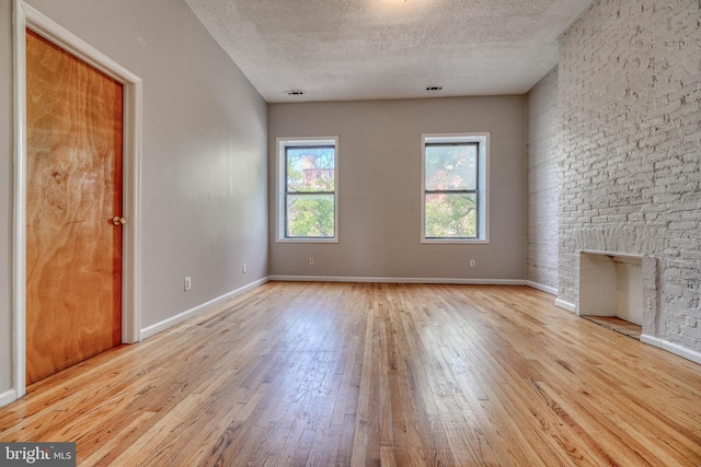 interior space featuring a textured ceiling, a fireplace, and light hardwood / wood-style flooring