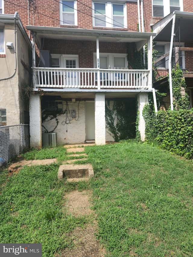 rear view of property with cooling unit and a yard