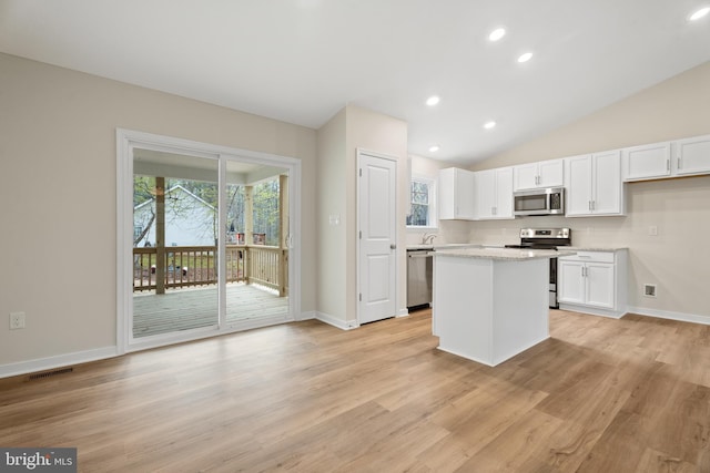 kitchen featuring white cabinetry, stainless steel appliances, a center island, and light wood-type flooring