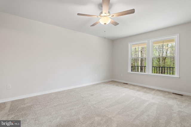 carpeted spare room featuring baseboards, ceiling fan, and visible vents