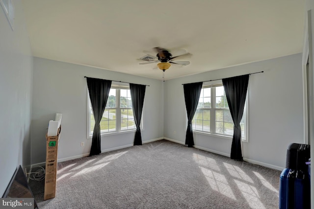 carpeted spare room with a wealth of natural light and ceiling fan