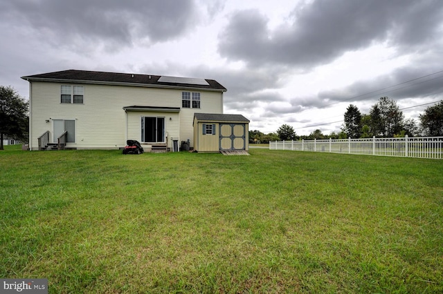 back of house with a storage shed and a yard