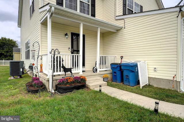 property entrance featuring a porch, a lawn, and central air condition unit