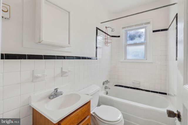 full bathroom with vanity, toilet, tile walls, and tiled shower / bath combo