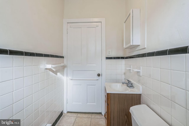 bathroom with tile patterned flooring, vanity, toilet, and tile walls