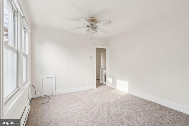 empty room with ceiling fan, light carpet, and a baseboard heating unit