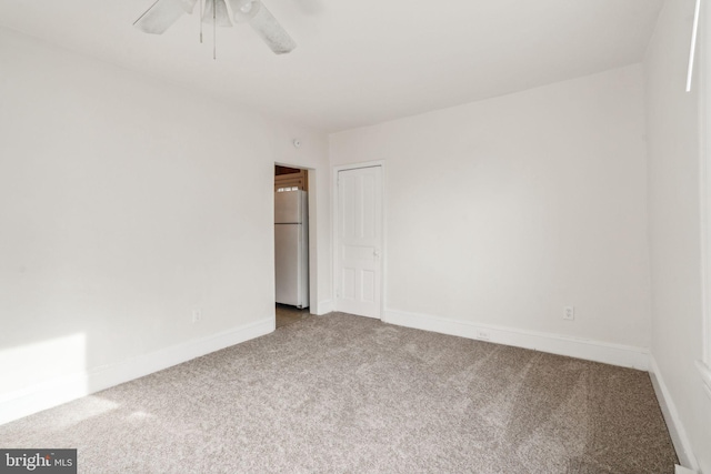 unfurnished bedroom featuring carpet, white refrigerator, and ceiling fan