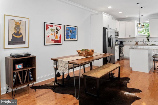 dining room featuring sink, ornamental molding, and light hardwood / wood-style flooring