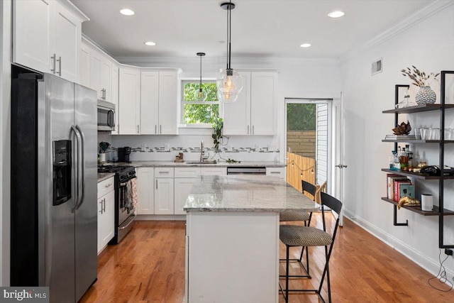 kitchen featuring pendant lighting, appliances with stainless steel finishes, white cabinets, and a kitchen island