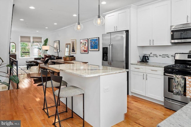 kitchen with stainless steel appliances, light hardwood / wood-style floors, white cabinets, crown molding, and pendant lighting