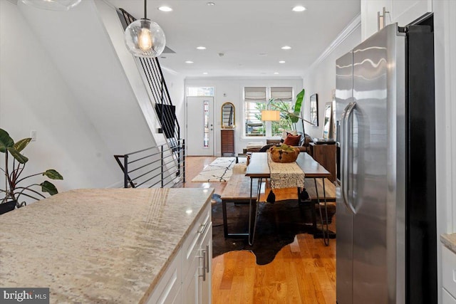 kitchen featuring white cabinets, stainless steel fridge with ice dispenser, light wood-type flooring, and crown molding