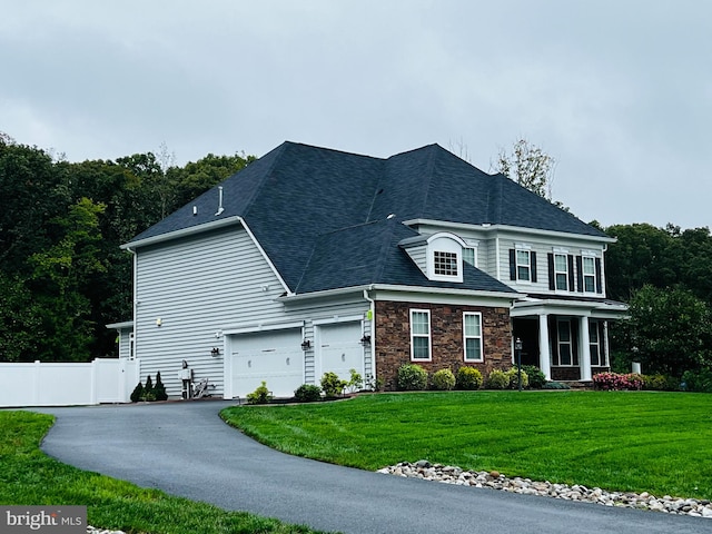 view of front of house featuring a front lawn, fence, aphalt driveway, stone siding, and an attached garage