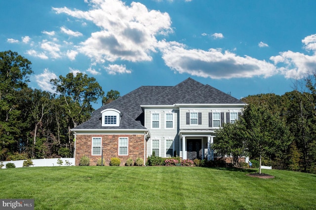 view of front of property featuring stone siding, roof with shingles, a front yard, and fence