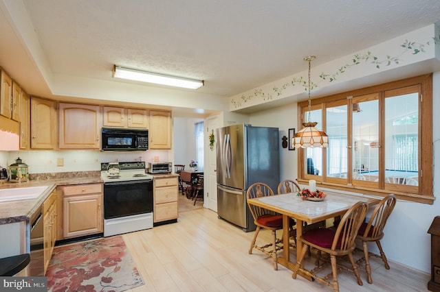 kitchen featuring a textured ceiling, decorative light fixtures, stainless steel appliances, light brown cabinetry, and light hardwood / wood-style floors