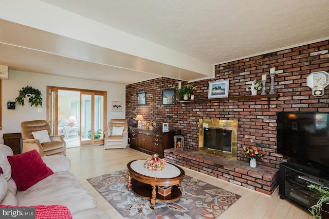 living room featuring brick wall, a textured ceiling, light hardwood / wood-style flooring, and a brick fireplace