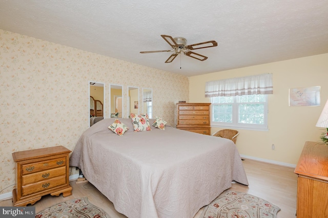 bedroom with ceiling fan, a textured ceiling, and light wood-type flooring