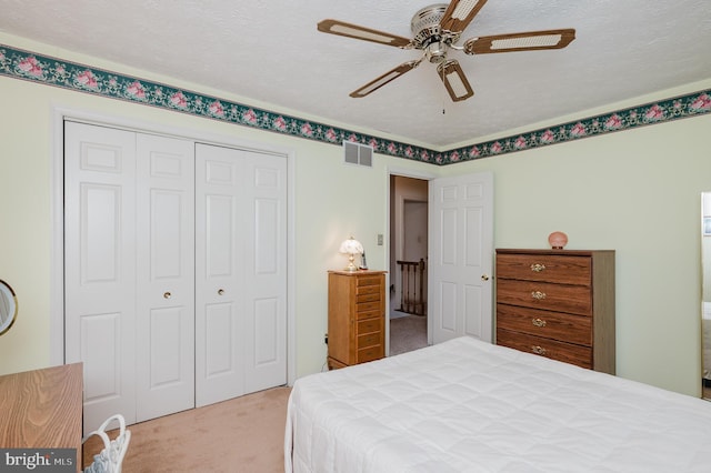 carpeted bedroom featuring a closet, ceiling fan, and a textured ceiling