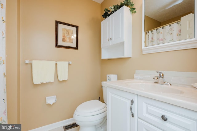 bathroom with vanity, toilet, and a textured ceiling