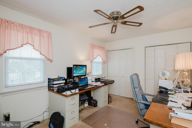 carpeted home office with a textured ceiling and ceiling fan