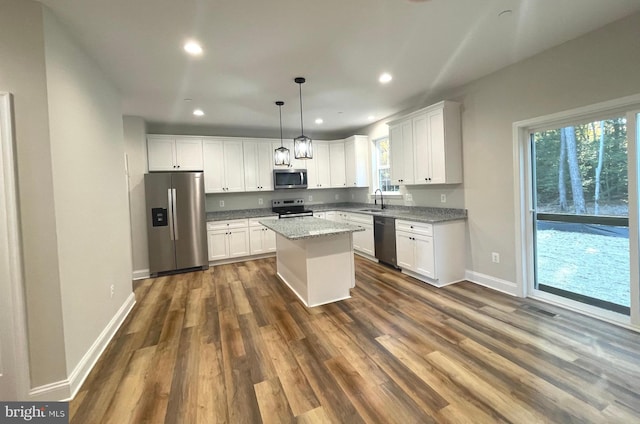 kitchen with a kitchen island, white cabinetry, appliances with stainless steel finishes, dark hardwood / wood-style floors, and hanging light fixtures