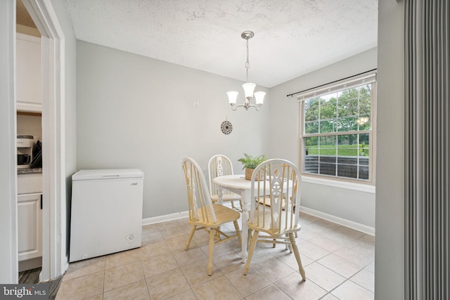 dining area featuring an inviting chandelier, light tile patterned floors, and a textured ceiling