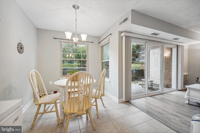 dining room featuring light hardwood / wood-style flooring, a notable chandelier, and a textured ceiling